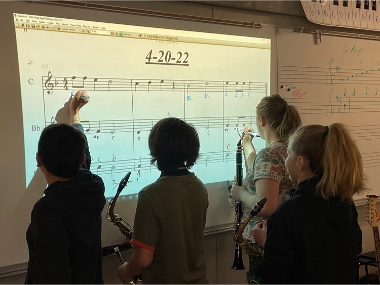 students marking up sheet music projected on a white board