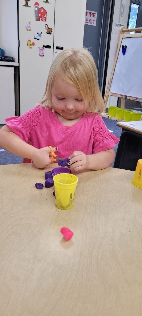 Lucy cutting Play-doh.
