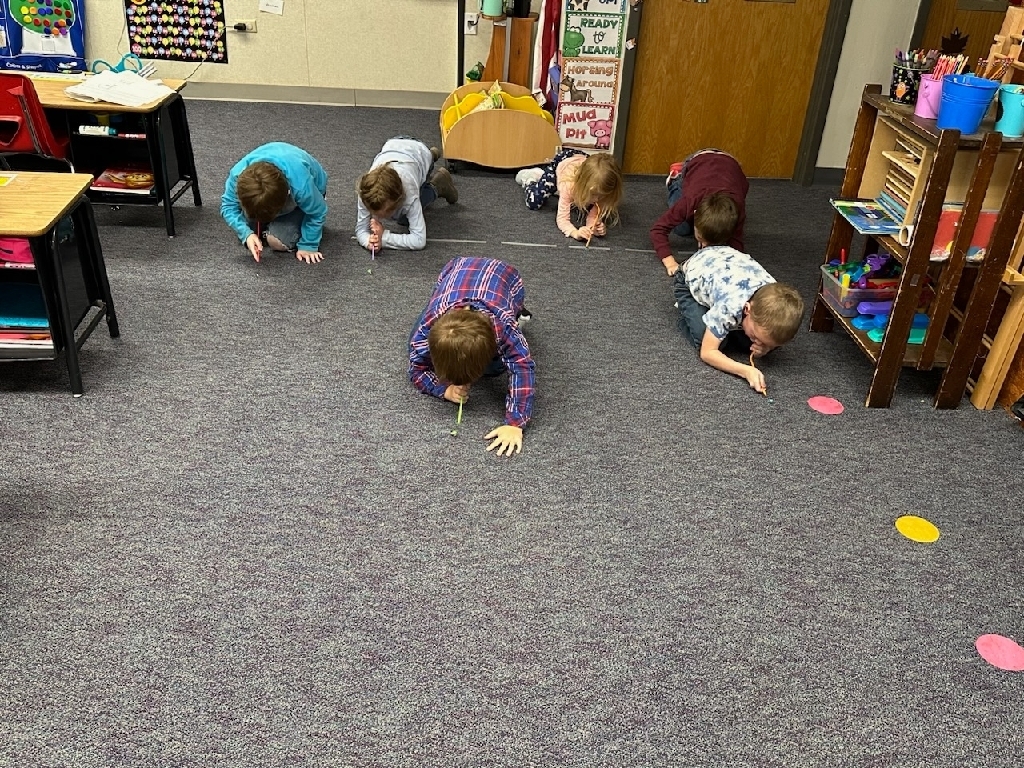 Kindergarten students blowing to move a marble.